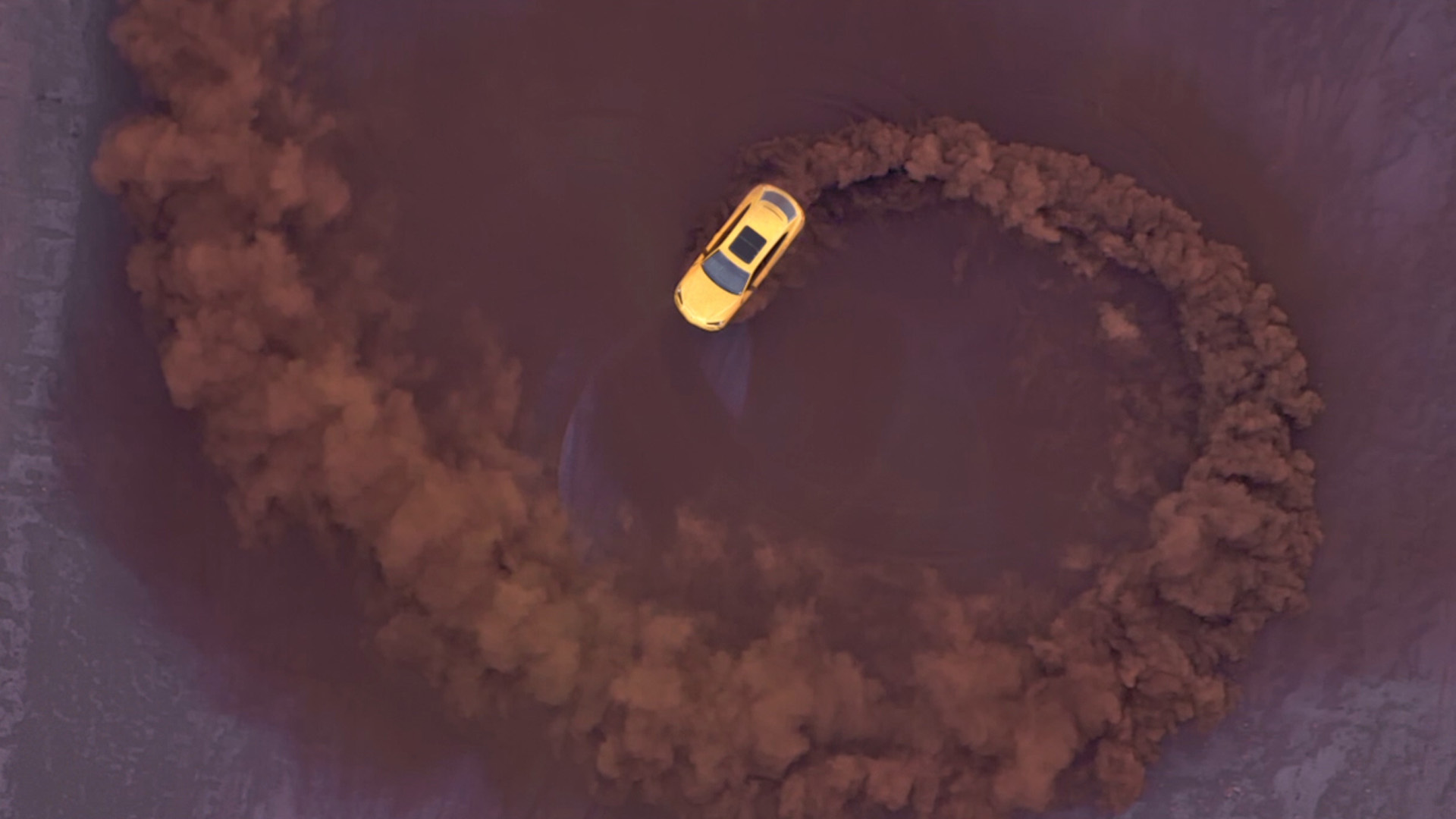 Lamborghini Urus gialla ripresa dall'alto mentre disegna un cerchio di polvere, frame dello spot di lancio